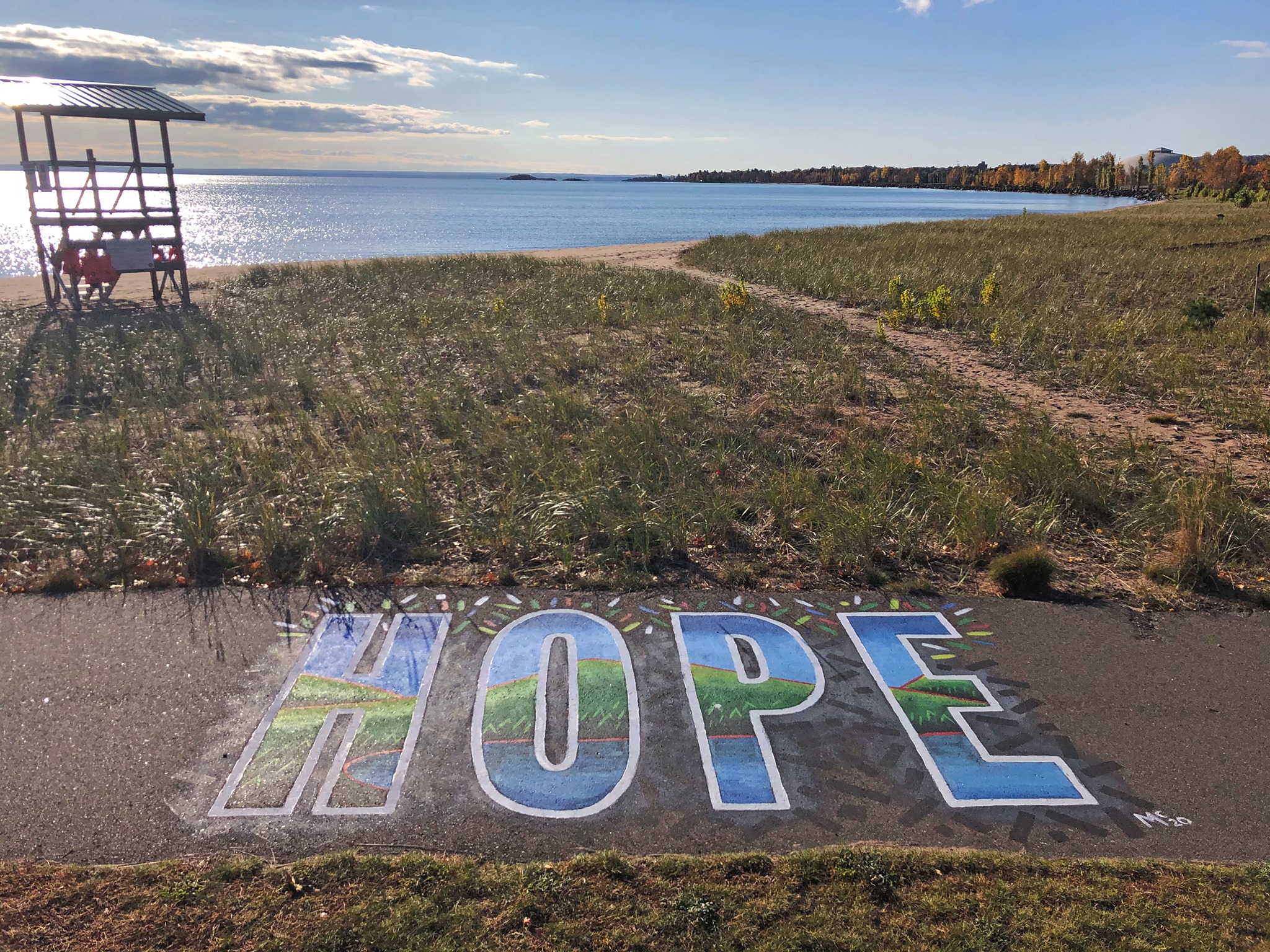 Hope Mural on the bikepath in front of the beach entrance with a lifeguard bench and lakeshore in the background